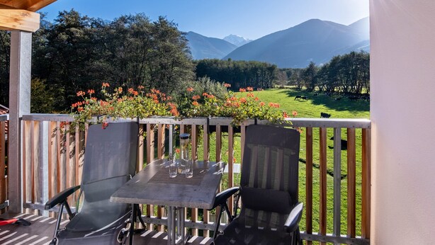 A balcony with a table and chairs, overlooking a grassy field and mountains. - Apartment 'Hausergut Bonita 1' with Mountain View, Shared Garden and Wi-Fi (Sluderno)