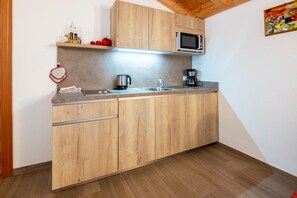 Una cucina con mobili in legno, un forno a microonde, un bollitore e una macchina da caffè.