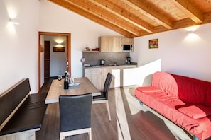 Una cucina moderna con mobili in legno, un tavolo da pranzo con sedie, un divano rosso e un soffitto in legno.