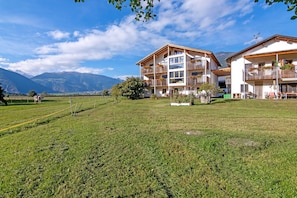 Un hôtel doté de nombreux balcons, d’une pelouse verdoyante et surplombant un paysage montagneux.