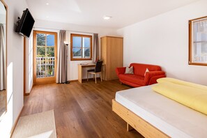 A room with a bed, a desk, a chair, a red sofa, a TV, and a wardrobe. - Studio Apartment 'Hausergut Topaz' with Mountain View, Shared Garden and Wi-Fi (Sluderno)