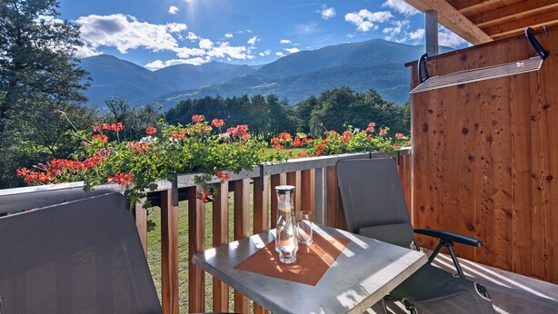 Een tafel met stoelen op een terras met uitzicht op een berg.