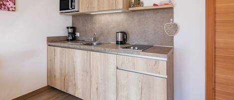 Een moderne keuken met houten kastjes, een magnetron, een koffiezetapparaat en een waterkoker.