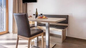 Een moderne eetruimte met een houten tafel, een gewatteerde bank en een stoel.