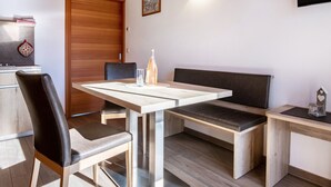 A modern kitchen with a wooden cabinet, a dining table with chairs, and a bench.