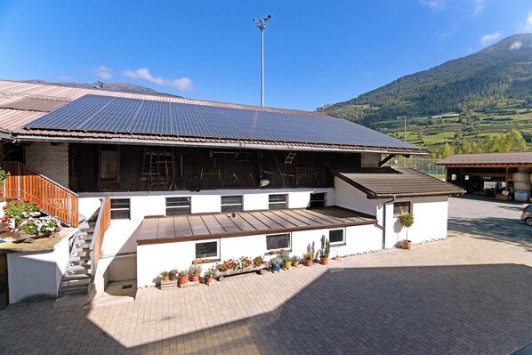 A building with a sloped roof, solar panels, a staircase, and potted plants.