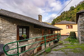 A stone building with a wooden staircase and a green railing. - Apartment 'El Rebocho' with Mountain View, Private Terrace and Wi-Fi (Cangas Del Narcea)