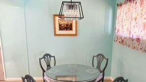 A dining area with a round glass table, four chairs, a chandelier, and a framed picture on the wall. - Cozy 3BR Home Near SF & Napa Valley (Vallejo)