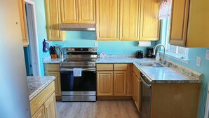 A kitchen with wooden cabinets, stainless steel appliances, a granite countertop, and a window with a curtain. - Cozy 3BR Home Near SF & Napa Valley (Vallejo)