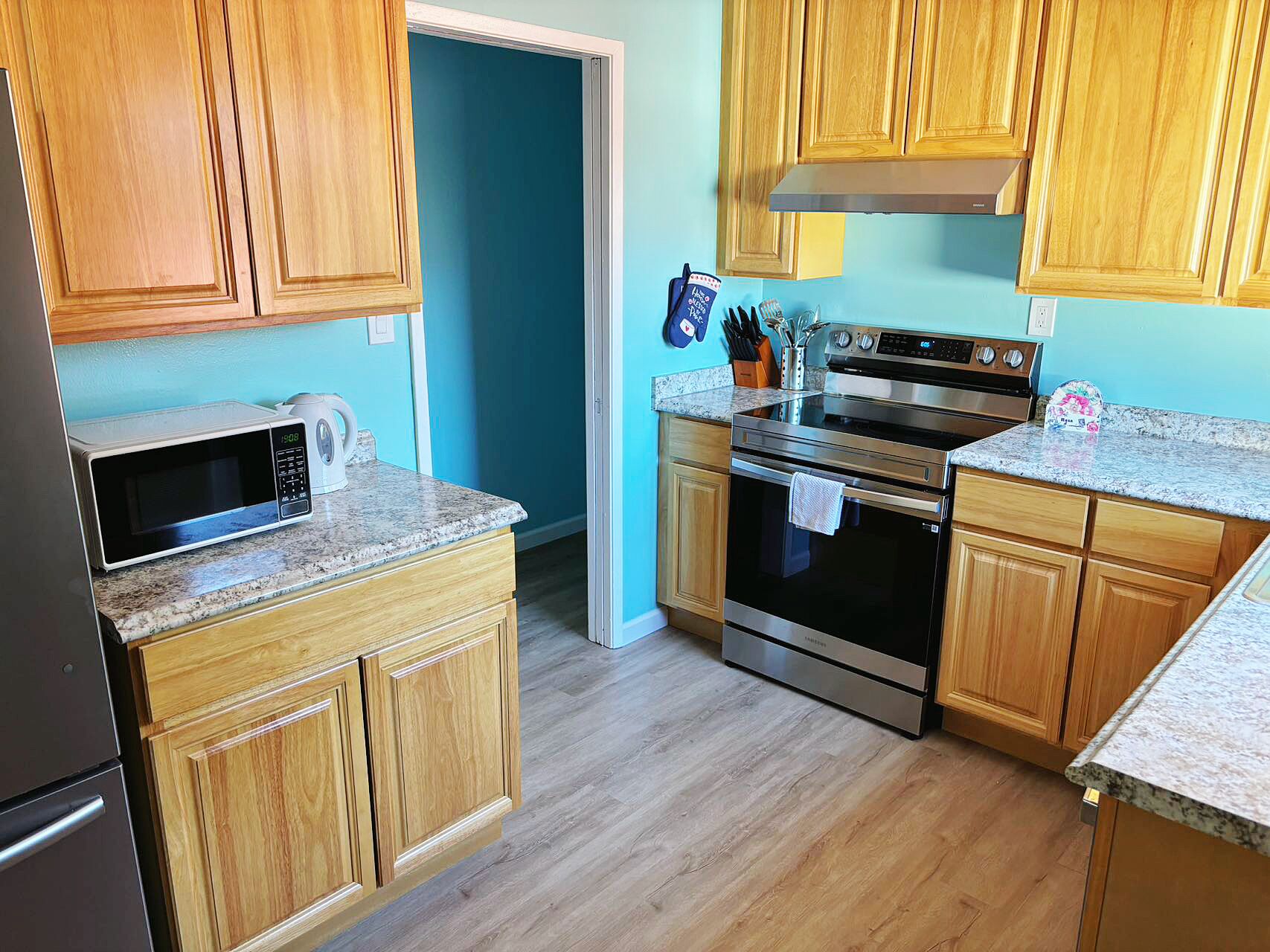 A kitchen with wooden cabinets, a stainless steel oven, a microwave, and granite countertops.