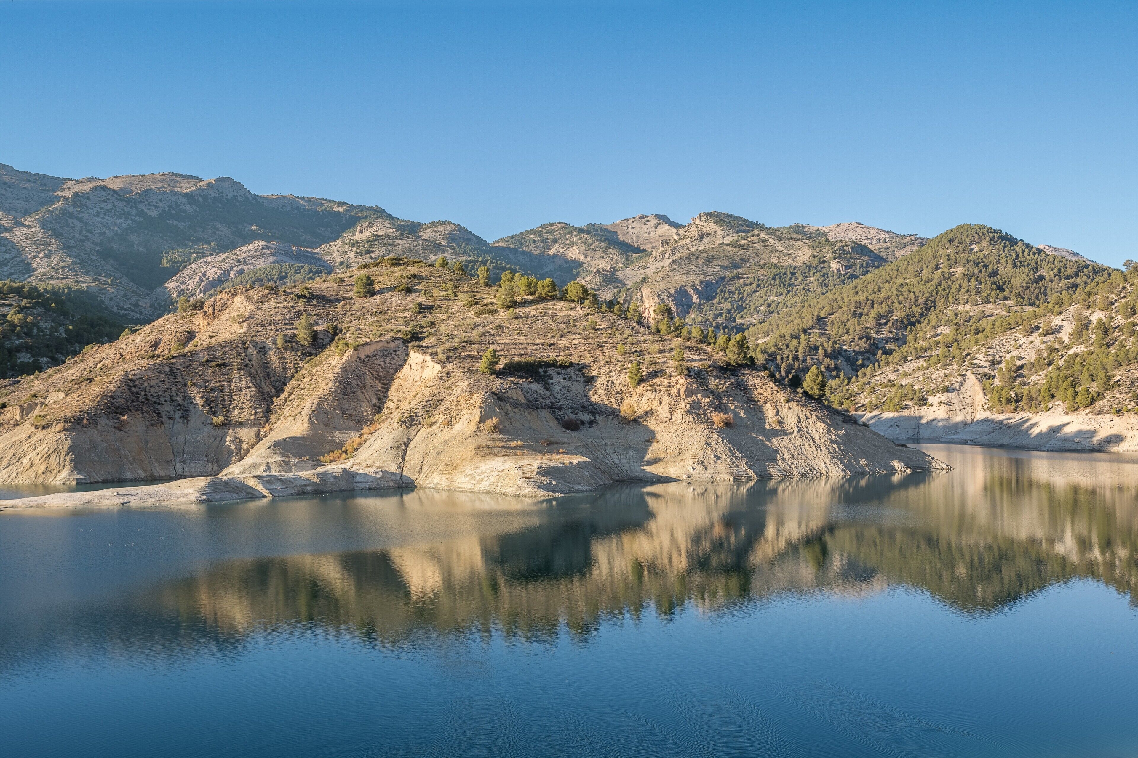 Un paysage montagneux avec un lac paisible qui reflète le relief environnant.