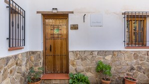A stone wall, a wooden door, and potted plants. - Apartment 'Casa Rural Cortijo El Plantio' with Mountain View, Wi-Fi and Air Conditioning (Granada)