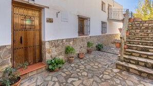 A rustic building with a wooden door, stone steps, and potted plants. - Apartment 'Casa Rural Cortijo El Plantio' with Mountain View, Wi-Fi and Air Conditioning (Granada)