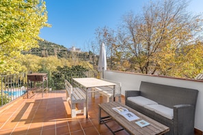 A terrace with a table, bench, and wicker sofa, overlooking a pool and trees. - Apartment 'Casa Rural Cortijo El Plantio' with Mountain View, Wi-Fi and Air Conditioning (Granada)