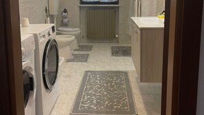 Een moderne badkamer met een wasmachine, toilet en een groot raam.