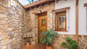 Un muro in pietra, una porta in legno e piante in vasi in un cortile.