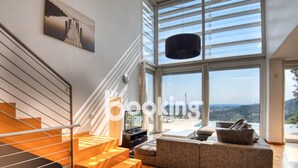 A modern interior with a staircase, a sofa, and a large window offering a view of the landscape. - Exclusive villa with sea views in Costa Brava (Calonge)