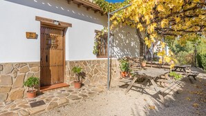 Un bâtiment à la façade en pierre, une porte en bois et une pergola aux feuilles jaunes.