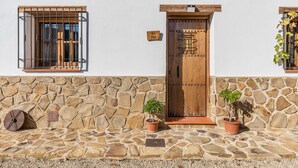 Un bâtiment avec une façade en pierre, une porte en bois et deux plantes en pot.