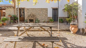 Un patio con muro de piedra, mesa de madera y plantas en macetas.