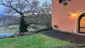 Ein Gebäude mit befestigtem Eingang, einem Baum und einer Rasenfläche.