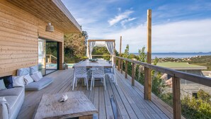 A wooden deck with a dining table and chairs, a sofa, and a view of the sea. - Villa 'Liliekaena' with Sea View, Wi-Fi, and Air Conditioning (Albitreccia)