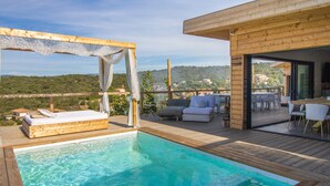 A wooden deck with a pool, outdoor seating, and a view of the landscape.