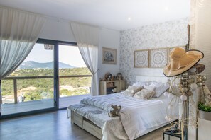 Un dormitorio con una cama grande, vistas al exterior y un elemento decorativo en la pared.