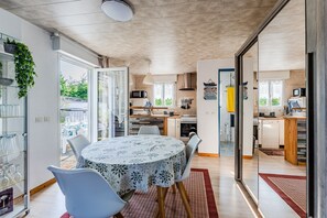 Eine moderne Küche mit Essbereich, einer Glastür, die nach draußen führt, und Blick auf den Garten.