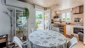 Une cuisine moderne avec un coin repas, un meuble vitré contenant des plantes et une vue sur l’extérieur.