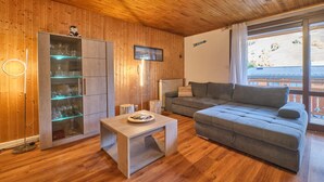 Una habitación con paneles de madera, un sofá, una mesa y un aparador con estantes de vidrio.