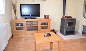 A living room with a television, wooden cabinet, and a fireplace. - Apartment 'Casa Requias 1' with Lake View, Shared Garden and Wi-Fi (Requiás)