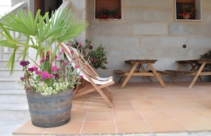 Une chaise en bois, une table en bois et une plante en pot avec des fleurs.