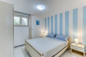 Une chambre à coucher avec un lit, une table de chevet, une fenêtre et un mur à rayures.