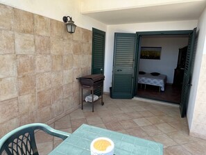 A small room with a bed, a table with a cup, and a chair.