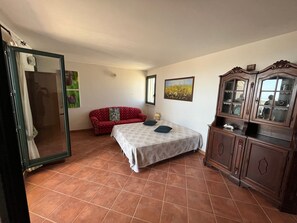 Une chambre à coucher avec un lit, un canapé rouge, une armoire en bois et un grand miroir.