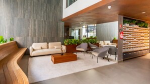 Un hall d’entrée moderne avec un canapé, des fauteuils, une table basse et un mur végétal.
