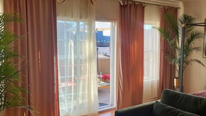 Een woonkamer met een groene bank, een kroonluchter en uitzicht door een glazen deur.
