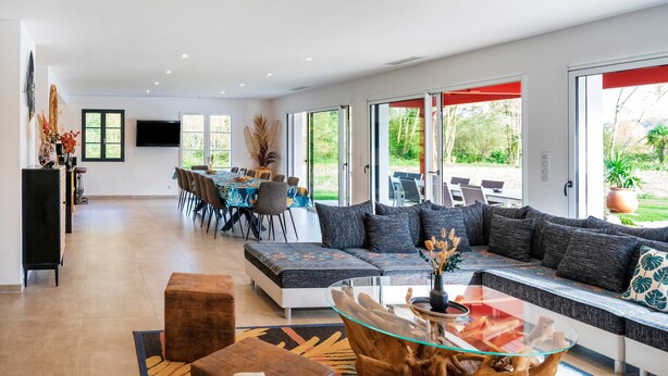 A modern living room with a sectional sofa, glass coffee table, and a dining area with chairs and a table. - Villa Zeruko Izarra 5***** Wi-Fi & Air Conditioning, Mountain Views (Sare)