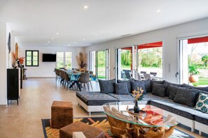 Una sala moderna con un sofá modular, una mesa de centro de vidrio y un comedor con sillas y una mesa.
