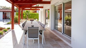 A covered patio with a long dining table, chairs, and a red pergola. - Villa Zeruko Izarra 5***** Wi-Fi & Air Conditioning, Mountain Views (Sare)