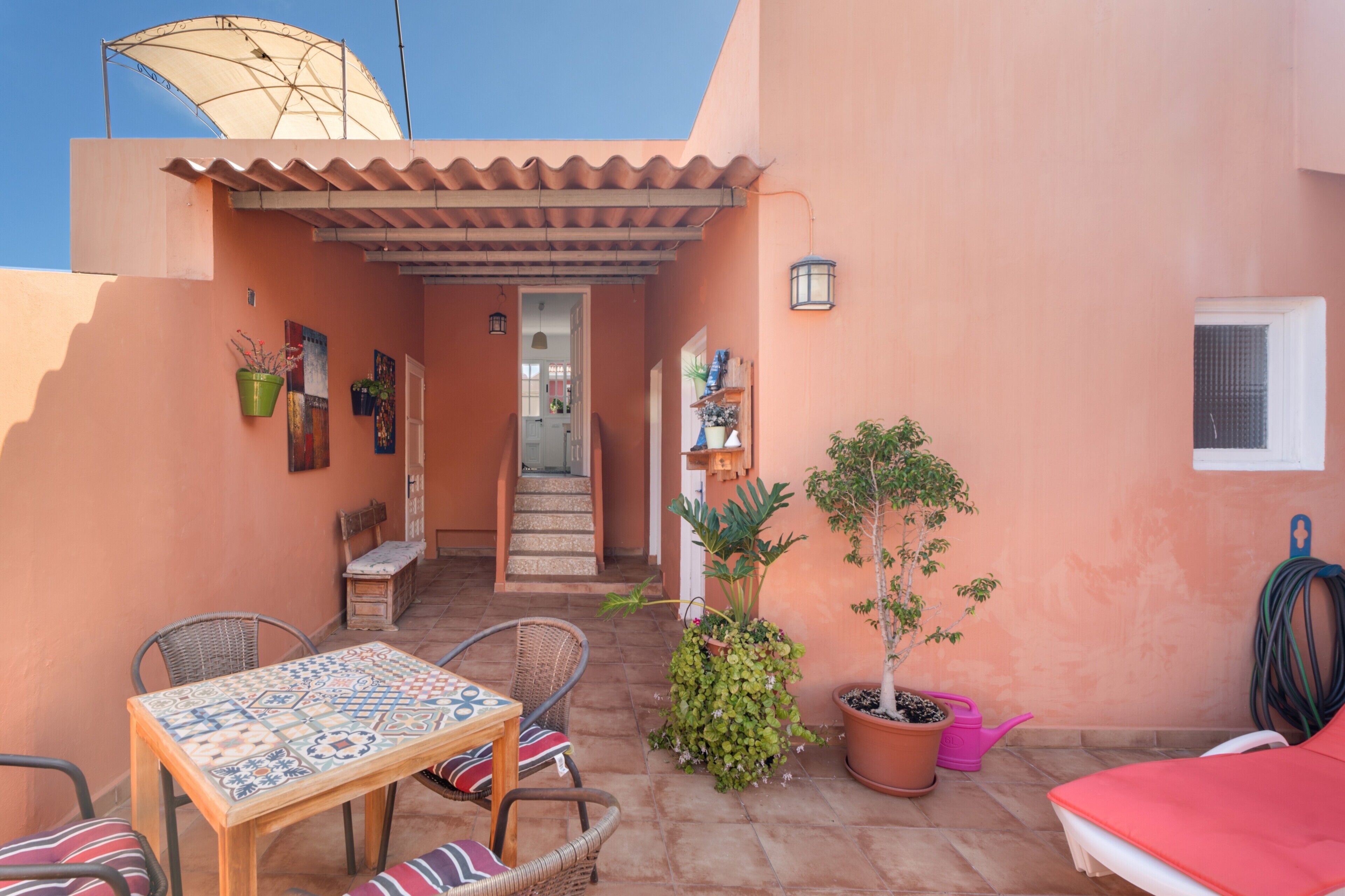 Un patio con tavolo e sedie, una pianta in vaso e una scala che conduce a un ambiente interno.