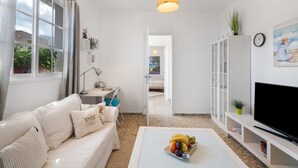 Een moderne woonkamer met een bank, salontafel, televisie en uitzicht op een andere kamer.