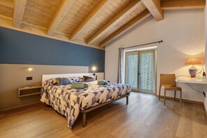 A bedroom with a bed, bedside tables, a desk, and a chair.