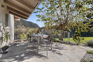 An outdoor patio with a table and chairs, surrounded by a metal fence, with a view of a mountain and a tree. - Holiday Home 'Appartamento Amaranto' with Mountain View, Shared Terrace and Wi-Fi (Tremosine s/Garda)