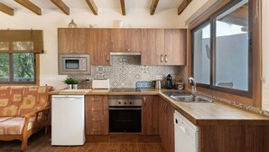 A compact kitchen with wooden cabinets, a built-in oven, a microwave, and a dishwasher.