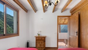 A bedroom with two beds, a wooden cabinet, a small table with a plant, and a view of a balcony.