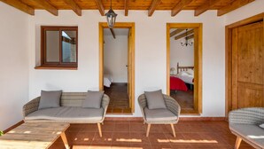 A room with a wooden ceiling, a sofa, a chair, a bed, and a mirror.
