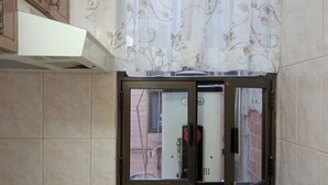 A kitchen with a gas stove, a window with a metal frame, and a decorative curtain. - Suite with moons of the Amazon River, by Reforma 222 (Ciudad de México)