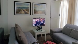 A living room with two sofas, a TV, and two framed pictures on the wall. - Suite with moons of the Amazon River, by Reforma 222 (Ciudad de México)
